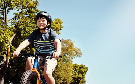 Cycling around the block. a young boy riding his bicycle through his neighbourhood.の写真素材