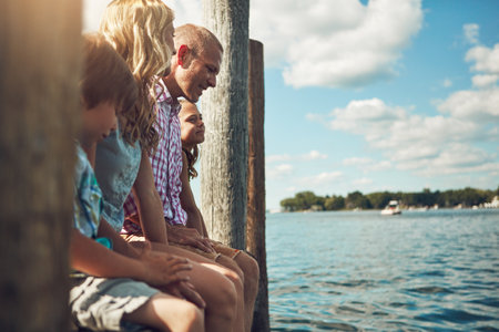 Time spent with family is worth every second. a young family on a pier while out by the lake.の写真素材