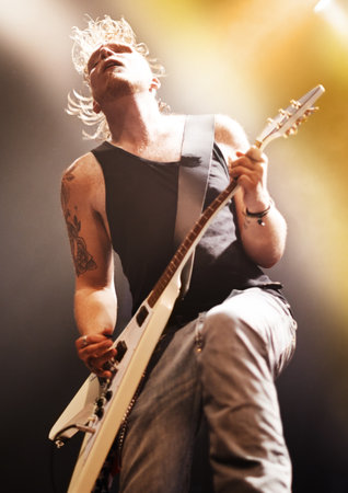 Music, concert and man with guitar on a stage for performance, passion or artistic freedom. Rock, festival and guy musician on electric musical instrument, live or rockstar event with metal aestheticの写真素材