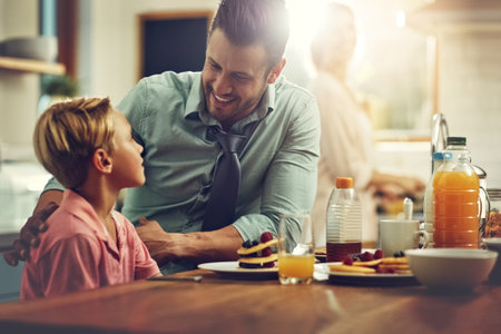 Family comes before business. a man sitting with his son while hes having breakfast.の写真素材