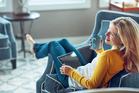 Youll always be entertained online. a young woman using her digital tablet while relaxing on her...
