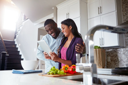 The internet is a great place to find food inspiration. a young couple using a digital tablet while preparing a healthy meal together at home.の写真素材