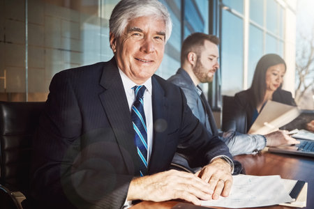 The boardroom is where we come to do business. Cropped portrait of a mature businessman sitting in the boardroom during a meeting.の写真素材