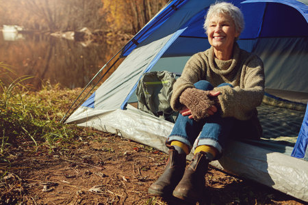 Life is about enjoying the simple things. a senior woman camping in the wilderness.の写真素材