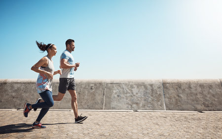 Keep moving forward. Full length shot of a young couple out for a run on the promenade.の写真素材
