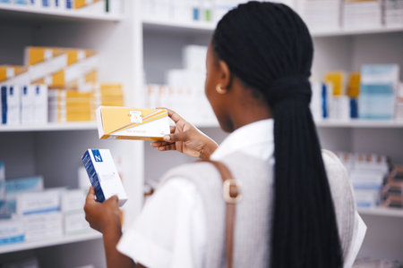 Pharmacy stock, woman and medicine check of a customer in a healthcare and wellness store. Medical, inventory and pharmaceutical label information checking of a black female person back by shop shelfの写真素材