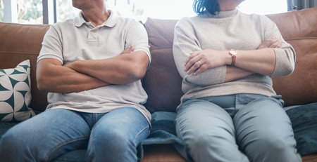 Angry couple, fight and arms crossed with divorce, marriage and break up problem in living room. Home, sofa and woman and man together with conflict and anger from frustration in a relationshipの写真素材