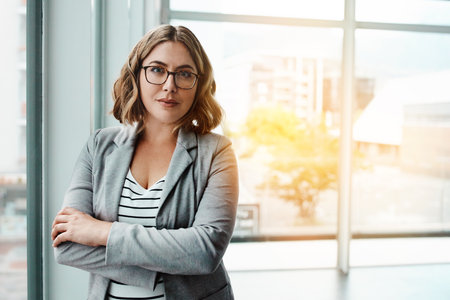 Never doubt yourself and all the great things you can achieve. Portrait of a confident young businesswoman standing in an office.の写真素材