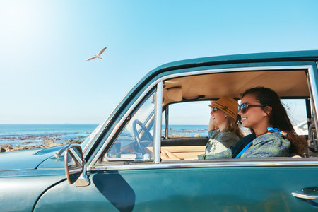 Rolling along the seaside. two friends on a road trip near the ocean.の写真素材