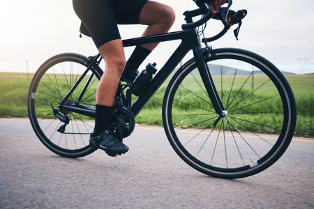 Closeup, legs and athlete on bicycle outdoor for exercise, training and triathlon sports. Person, bike and cycling on road for freedom, cardio fitness and performance with speed, power and transportの写真素材