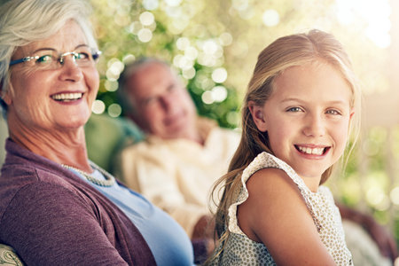 I love coming to grannys. Cropped portrait of a young girl sitting outside with her grandparents.の写真素材