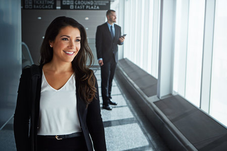Non-stop to success, now boarding. two executive businesspeople walking through an airport during a...