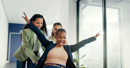 Office, celebration or happy women push chair to celebrate business profit, investment growth or startup success. Diversity, fun excited people playing or throw financial documents of company revenueの写真素材