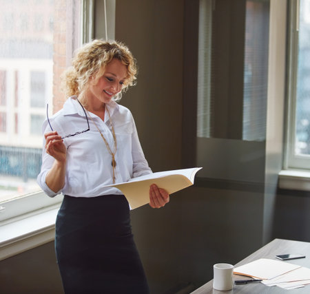 Using her professional strengths to benefit business. a businesswoman reading a report in an office.