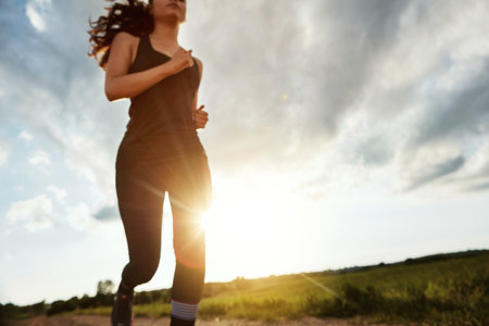 Just keep moving forward. a fit young woman out for a run on a beautiful day.の写真素材