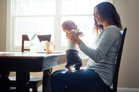 Hes growing up so fast already. a mother holding her newborn baby while sitting at a table in front...