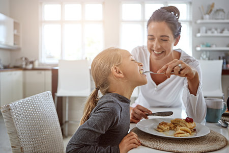 You can never go wrong with pancakes. a mother and daughter having breakfast at home.の写真素材