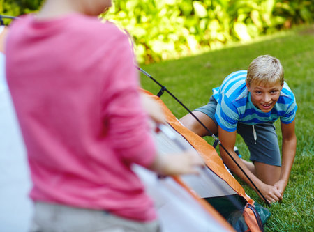 Right, first step pitching the tent. two young boys putting up their tent.の写真素材