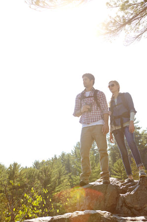 Theyre ready for the next trail...A young couple standing atop a moutain and taking into the view.の写真素材