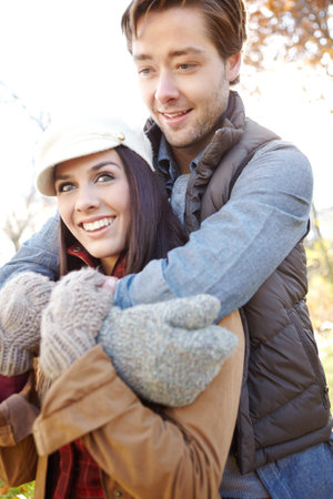 Autumn lovin. A handsome young man embracing his girlfriend while they spend time out in nature.の写真素材