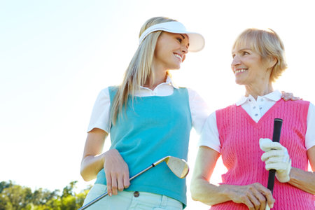 Golfing buddies with mom. Two attractive woman holding golf clubs and standing with their golf cart.の写真素材