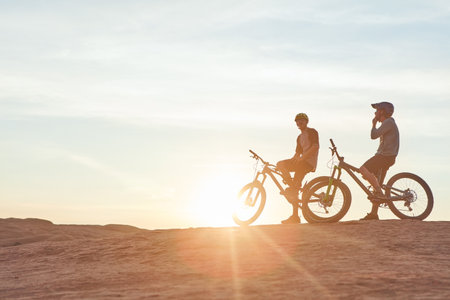 Focused on the road ahead. Full length shot of two young male athletes mountain biking in the wilderness.の写真素材