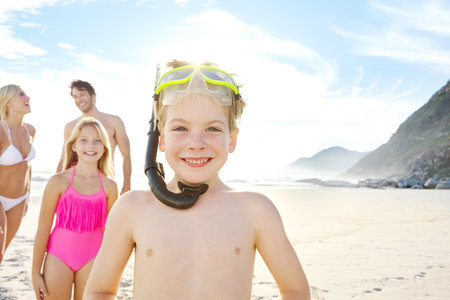 Lets go snorkelling. a happy little boy wearing goggles while spending a day with his family at the beach.の写真素材