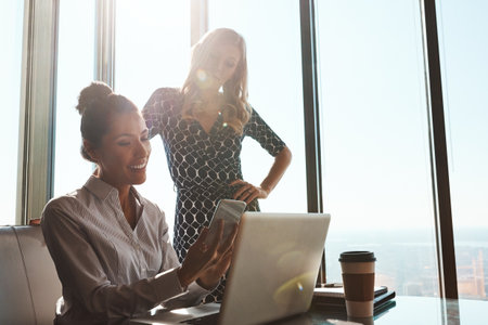 Tell me what you think...two attractive young businesswomen working in a modern office.の写真素材