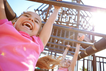 The best things in life arent things. two little girls hanging on the monkey bars at the playground.の写真素材