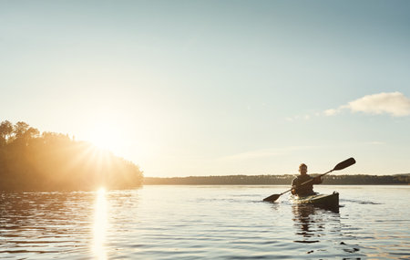 Exploring the outdoors one paddle at a time. a young man kayaking on a lake outdoors.の写真素材