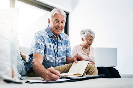 Balancing the household books. a senior couple going through their paperwork together at home.の写真素材