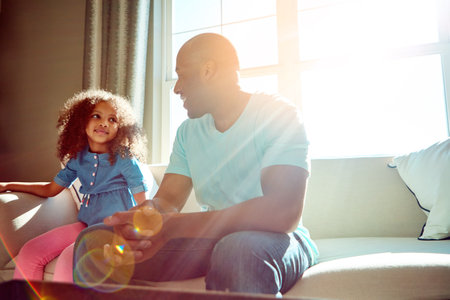 They never run out of things to talk about. a happy little girl and her father having a conversation while relaxing on the couch at home.の写真素材