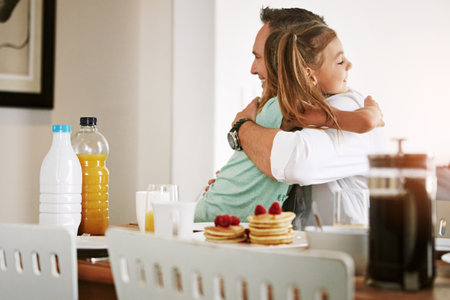 Have a great day at work, Dad. a little girl hugging her father at the breakfast table.の写真素材