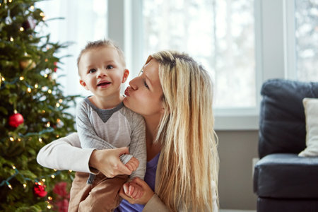 Give momma some kisses. a young mother enjoying Christmas with her little boy.の写真素材