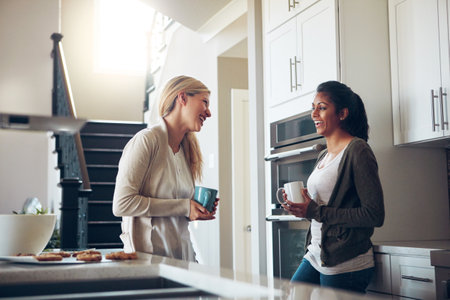 Happiness is time spent with your best friend. two young women having coffee together on a relaxing day at home.の写真素材