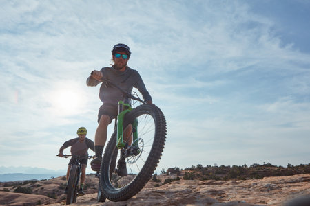 Know your limits and defy them. Full length shot of two athletic men mountain biking through the wilderness.