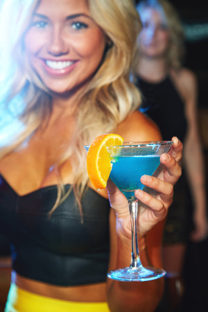 Getting the party going with a fruity cocktail. a young woman partying in a nightclub.の写真素材