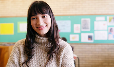 This is where I should be. Portrait of a cheerful young female teacher standing inside of her classroom during the day.の写真素材