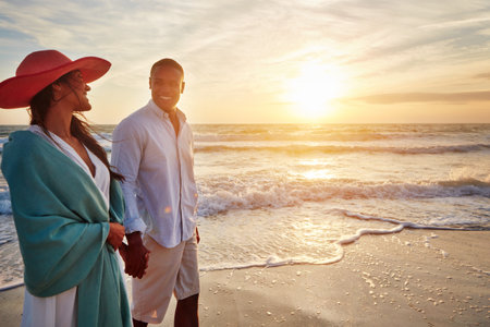 Its a special day for our love. a young couple taking a romantic stroll on the beach at sunset.の写真素材