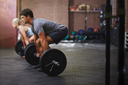 They drive each other to the next level. two people lifting weights in a gym.の写真素材