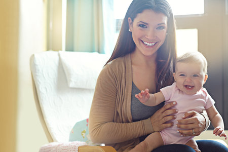Shes a lovable little handful. Portrait of a mother holding her baby girl at home.の写真素材