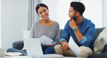 Getting her to explain her spending habits. a happy young couple sitting on the sofa while going...