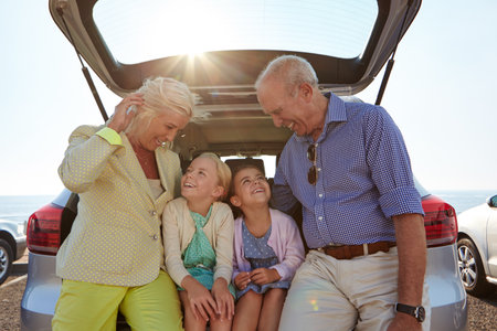 Grandkids light up your life. two little girls sitting in the trunk of a car with their grandparents.の写真素材