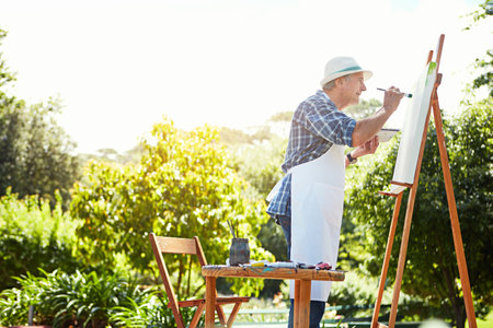 Adding a little colour to his canvas. a senior man painting in the park.の写真素材
