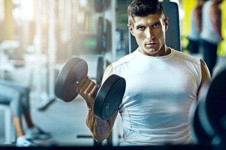 Now is the perfect time to start. a young man working out alone in the gym.の写真素材
