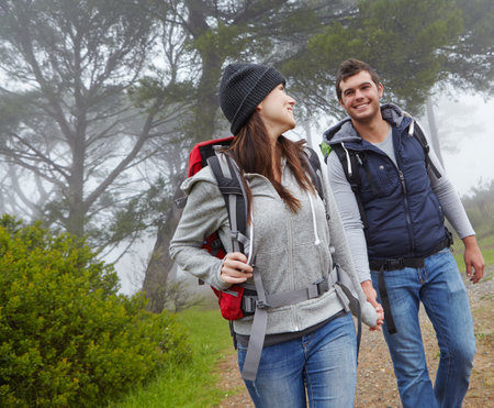 Hiking partners. a young couple hiking along a forest trail.の写真素材