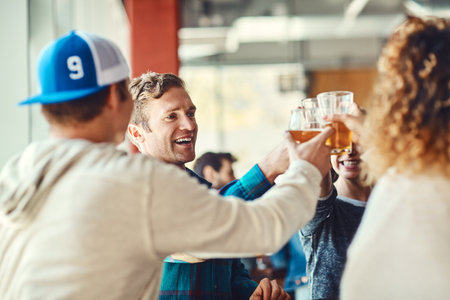 Lets start celebrating. a group of happy friends toasting with beers at a bar.の写真素材