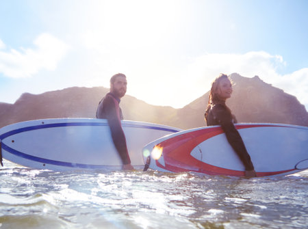 Into the wave wonderland. a young couple out surfing together.の写真素材
