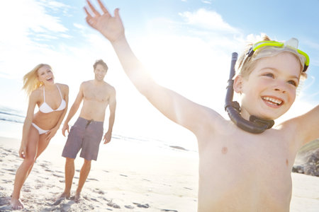 Unadulterated fun. a happy little boy wearing goggles while spending a day with his parents at the beach.の写真素材