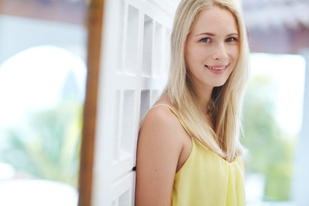 Enjoying the quiet of home. Portrait of a beautiful young woman standing in a hallway at home.の写真素材